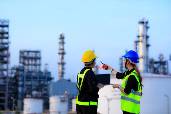 Two female engineers look over a refinery.