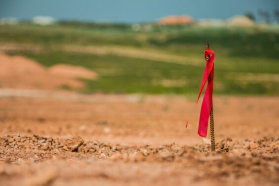 Metal survey peg with red flag on construction site